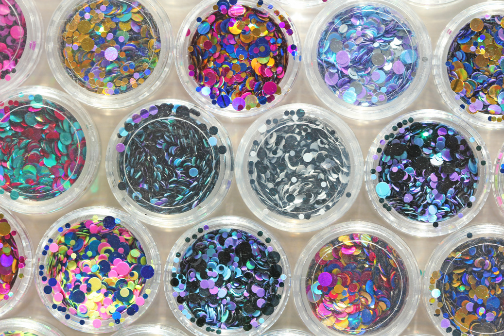 Multi colored Sequins for the design of nails in a Jar. Glitter in jars. Foil for nail service. Photo set. Sparkling beauty shimmer, glitter. Bright background of glitter. Top view